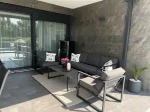 Modern családi ház homlokzata, ahol a sötétszürke kőfurnér burkolat és a fehér vakolat elegáns kontrasztot alkot, prémium megjelenést biztosítva.