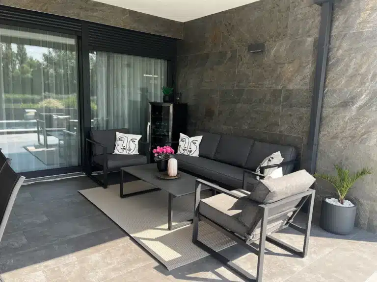 Modern családi ház homlokzata, ahol a sötétszürke kőfurnér burkolat és a fehér vakolat elegáns kontrasztot alkot, prémium megjelenést biztosítva.